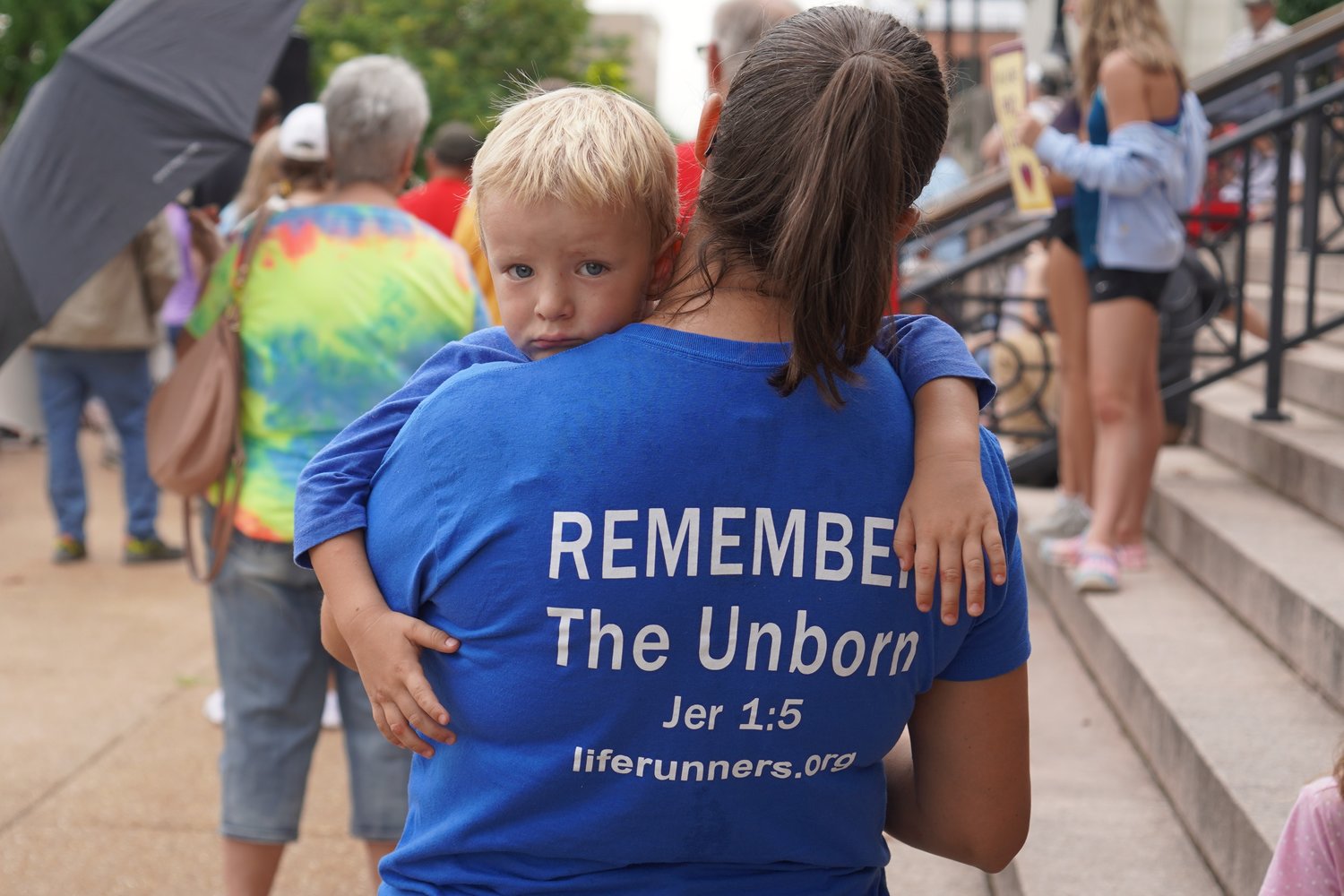 A woman wearing a LIFE Runners shirt holds a child outside the Missouri Supreme Court Building in Jefferson City in a Decision Day Rally on June 24, 2022, the day the U.S. Supreme Court overturned the 1973 decision that legalized abortion-on-demand throughout the country.